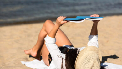 Persona relajada en una playa, con un teléfono móvil apagado en la distancia