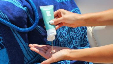 Persona aplicándose crema solar en la playa