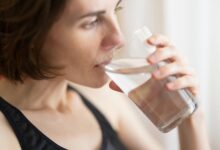 Una persona bebiendo un vaso de agua en la mañana