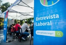 Persona sonriente con un traje y una carpeta en la mano, simbolizando el empleo