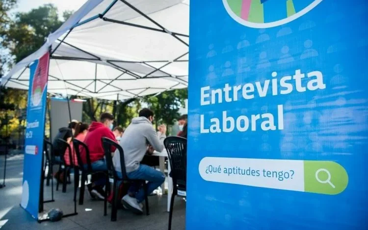 Persona sonriente con un traje y una carpeta en la mano, simbolizando el empleo