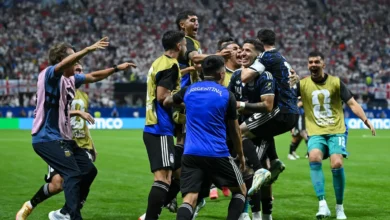 La Selección Argentina en acción en la cancha, con la bandera argentina ondeando en el aire.