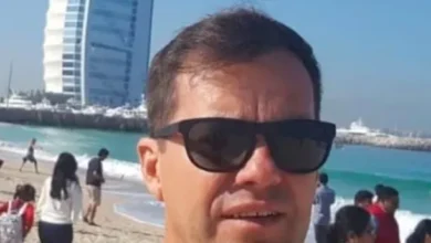 Imagen de un director de escuela en su escritorio, con un fondo de aulas y estudiantes