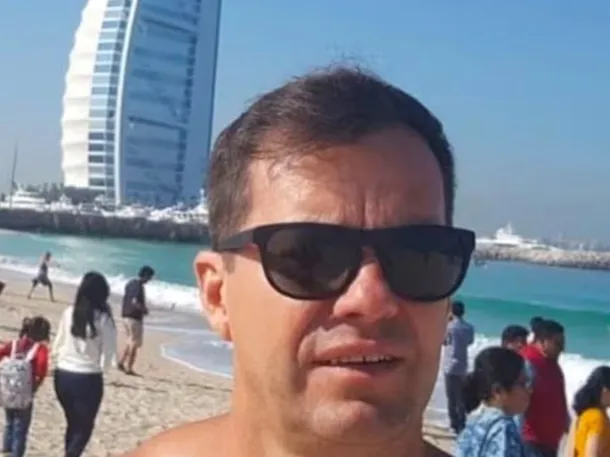 Imagen de un director de escuela en su escritorio, con un fondo de aulas y estudiantes