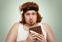 Joven atleta oliendo chocolate negro antes de una serie de extensiones de piernas