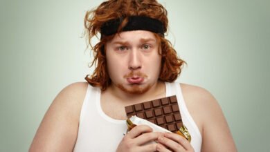 Joven atleta oliendo chocolate negro antes de una serie de extensiones de piernas