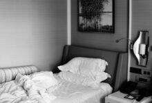 Cama sin hacer con sábanas arrugadas y almohada en una habitación luminosa
