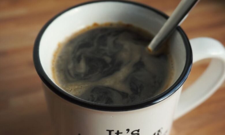 Taza de café humeante sobre una mesa de madera, símbolo de la rutina matutina