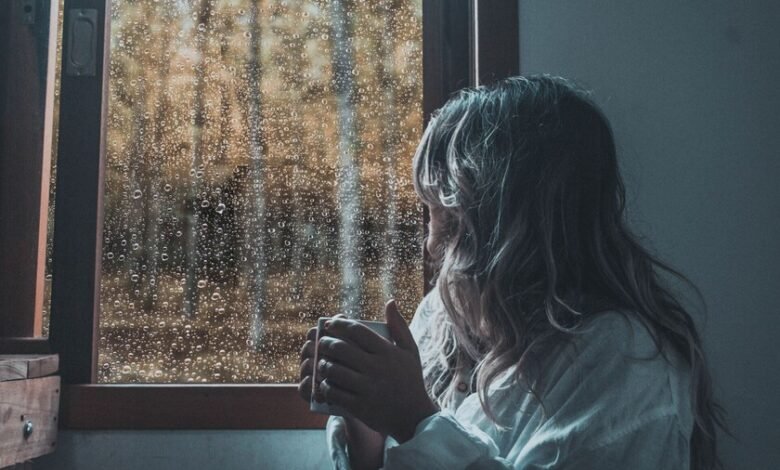 Persona tomando mate mientras escucha la lluvia en una ventana de Córdoba